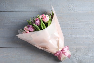 Photo of Bouquet of beautiful tulips on grey wooden table, top view