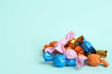 Candies in colorful wrappers on light blue background. Space for text