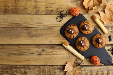 Photo of Delicious cookies decorated as monsters on wooden table, flat lay with space for text. Halloween treat