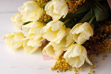 Bouquet with beautiful tulips and mimosa flowers on white marble table