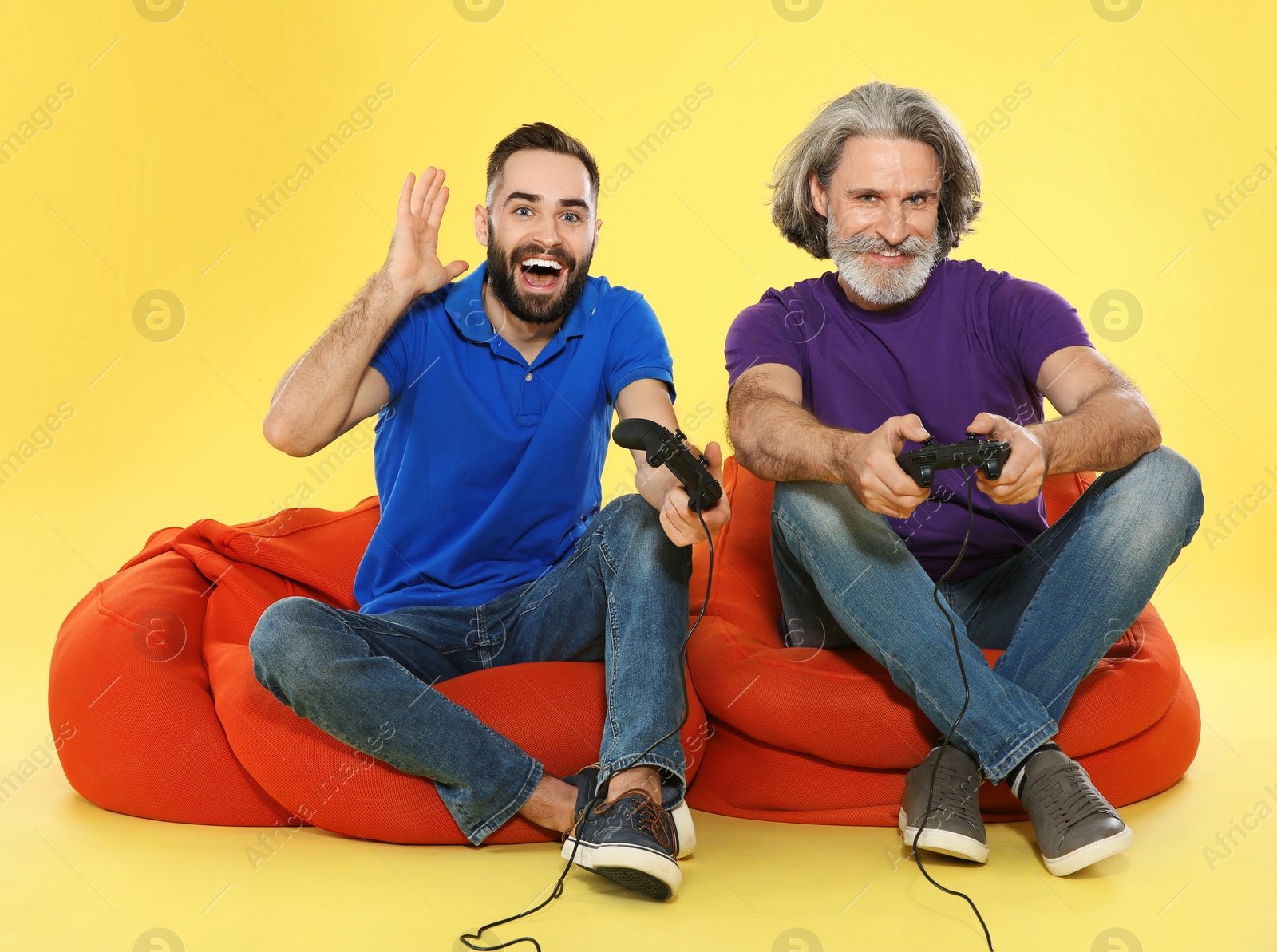 Photo of Mature man and guy playing video games with controllers on color background