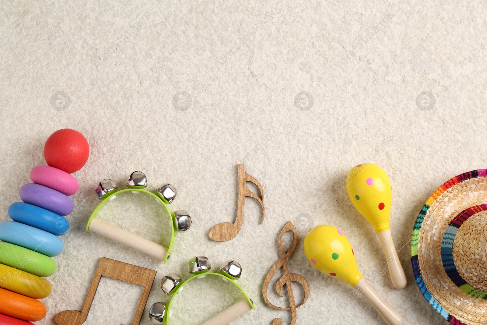 Photo of Baby song concept. Wooden notes, kids musical instruments and toys on beige carpet, flat lay. Space for text