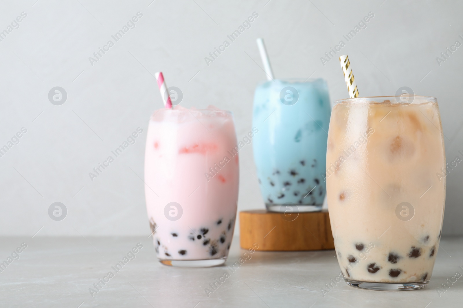 Photo of Different milk bubble teas on light grey table