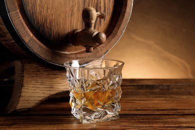 Glass of whiskey and wooden barrel on table, closeup