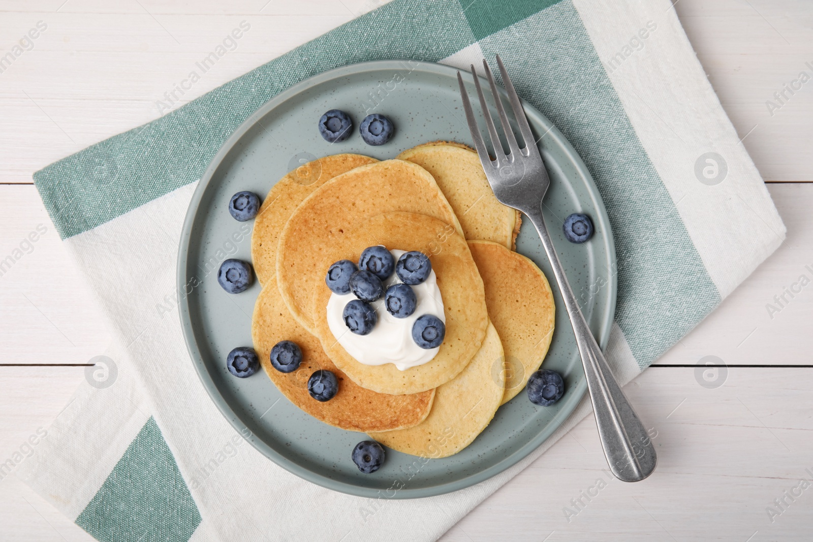 Photo of Tasty pancakes with natural yogurt and blueberries on white wooden table, flat lay