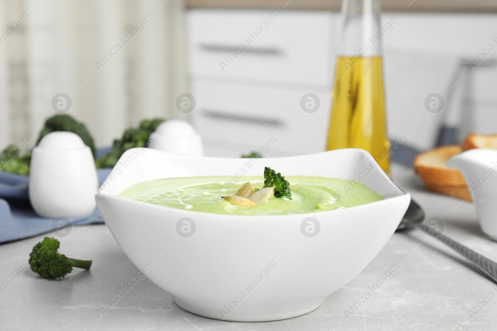 Photo of Delicious broccoli cream soup served on grey marble table indoors