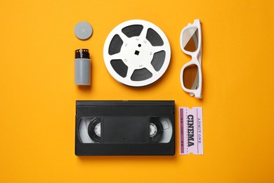 Flat lay composition with film reel and cinema ticket on orange background