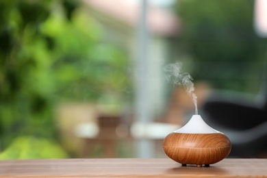 Photo of Aroma oil diffuser lamp on table against blurred background