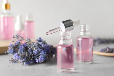 Photo of Bottles of essential oil and lavender flowers on stone table