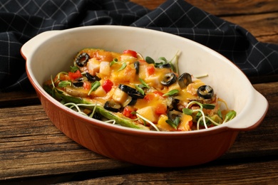 Photo of Baking dish with delicious stuffed zucchinis served on wooden table, closeup