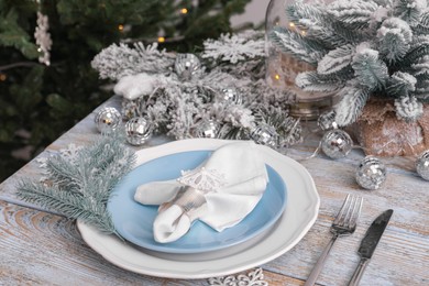 Photo of Festive place setting with beautiful dishware, cutlery and fabric napkin for Christmas dinner on light blue wooden table