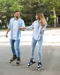 Young happy couple roller skating on city street