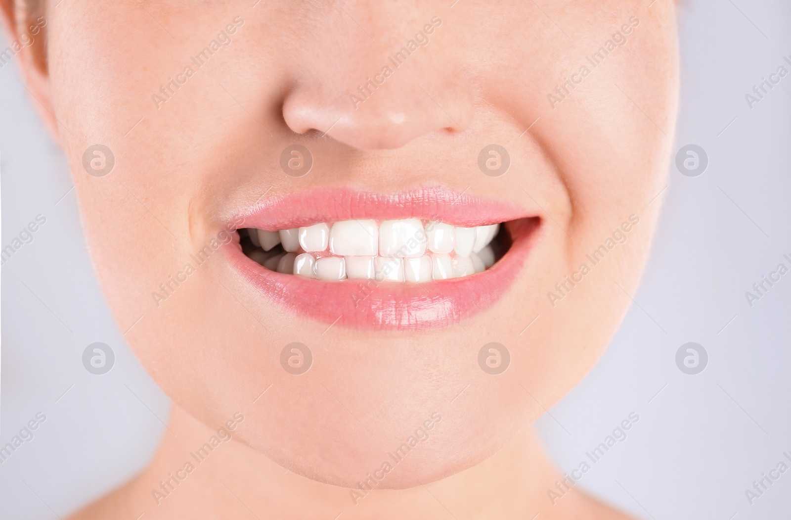 Photo of Young woman with beautiful smile on light background, closeup