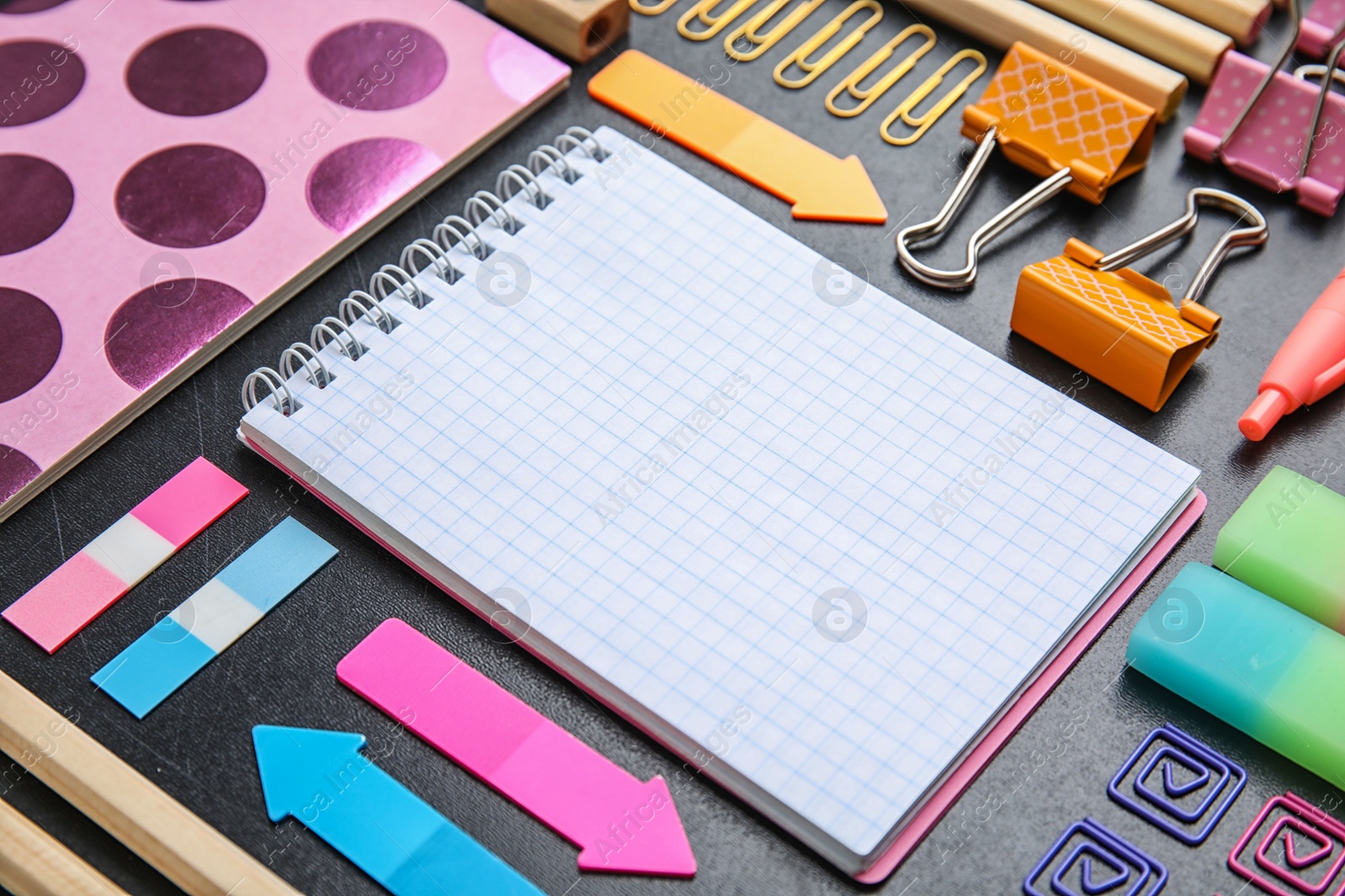 Photo of Different colorful stationery on chalkboard surface. Back to school