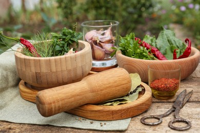 Photo of Mortar with pestle and different ingredients on wooden table outdoors