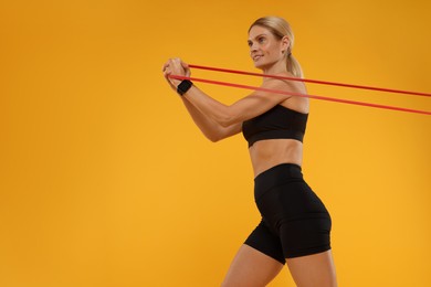 Photo of Woman exercising with elastic resistance band on orange background, low angle view. Space for text