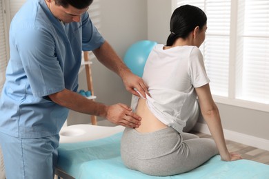 Photo of Orthopedist examining woman's back in clinic. Scoliosis treatment