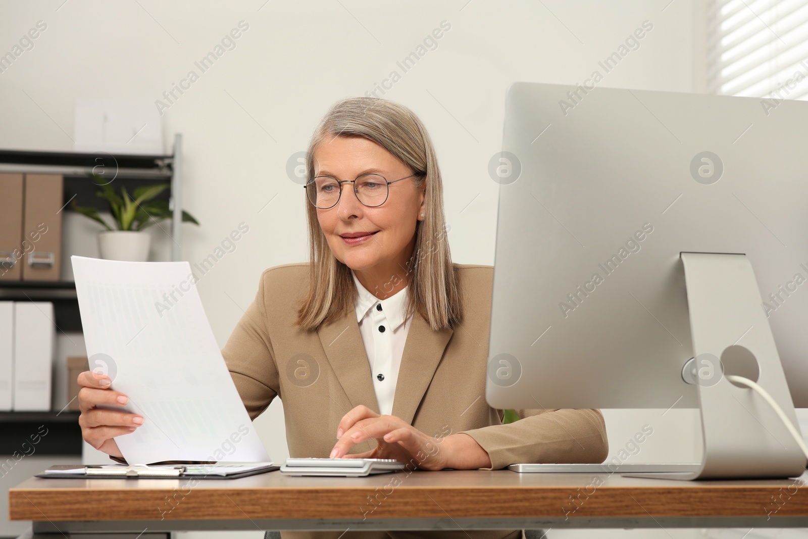 Photo of Senior accountant working at wooden desk in office