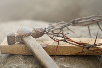 Crown of thorns, wooden plank and hammer on stone, closeup. Easter attributes