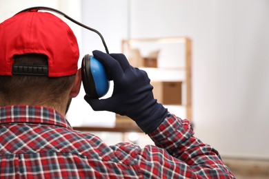 Photo of Worker wearing safety headphones indoors, back view. Hearing protection device