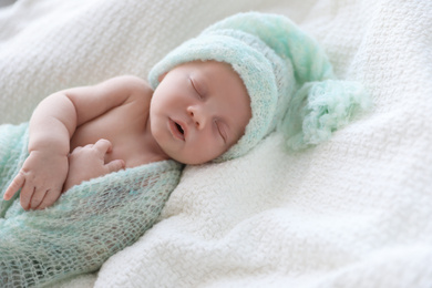 Photo of Cute newborn baby in warm hat sleeping on white plaid