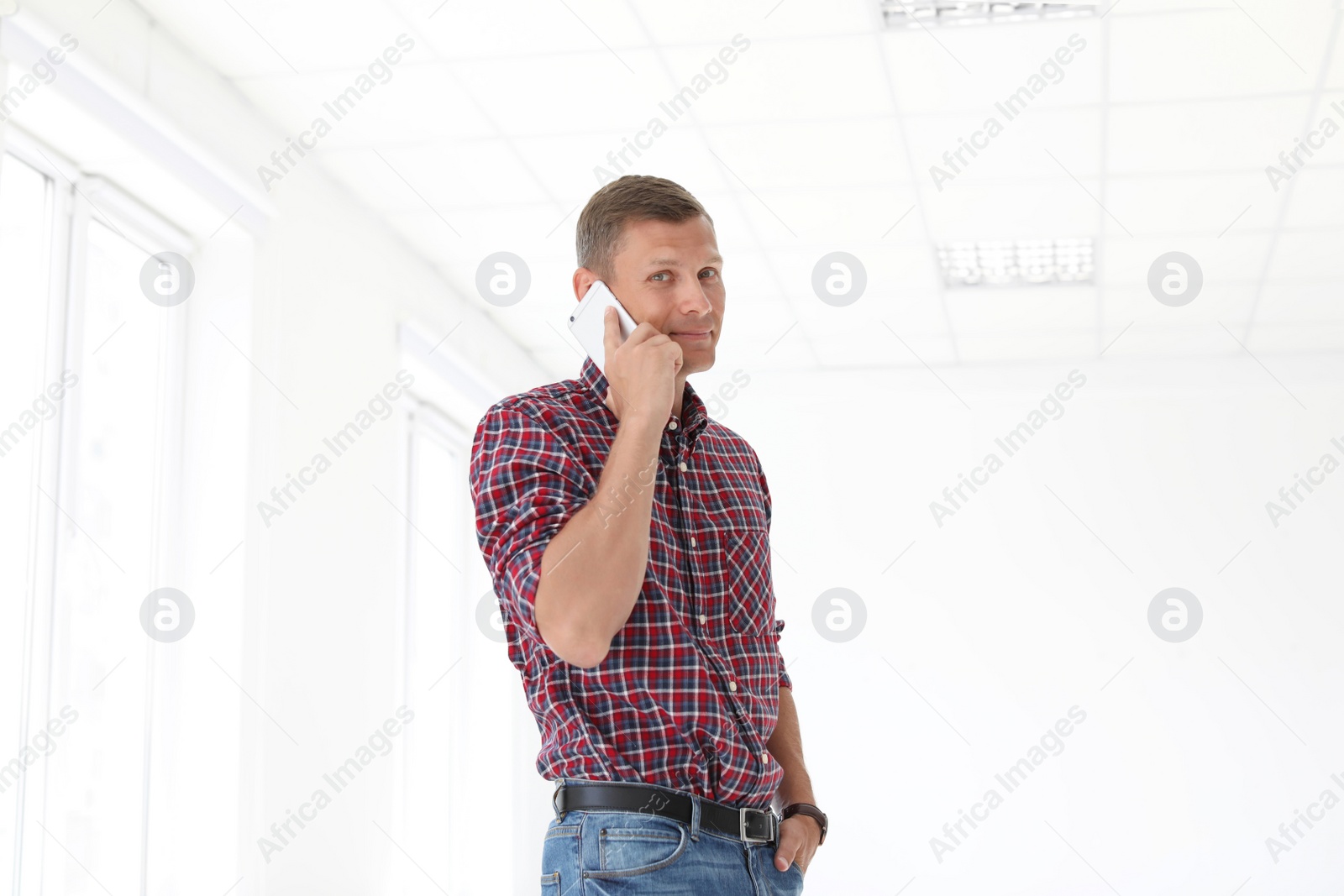 Photo of Young man talking on phone in office. Time to work