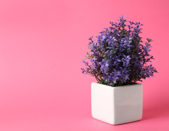 Beautiful artificial plant in flower pot on pink background, space for text