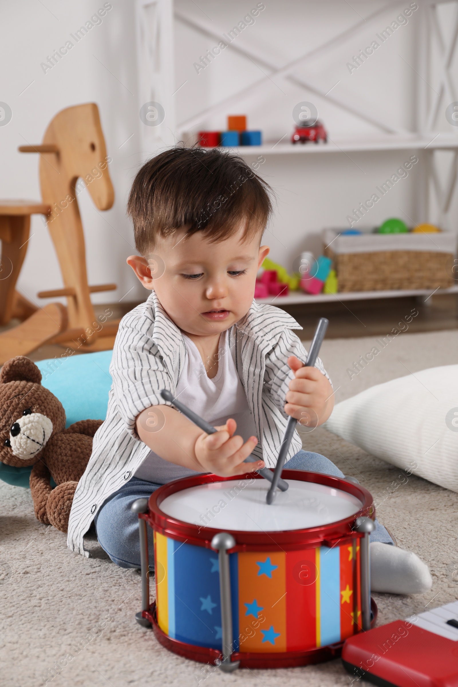 Photo of Cute little boy playing toy drum at home