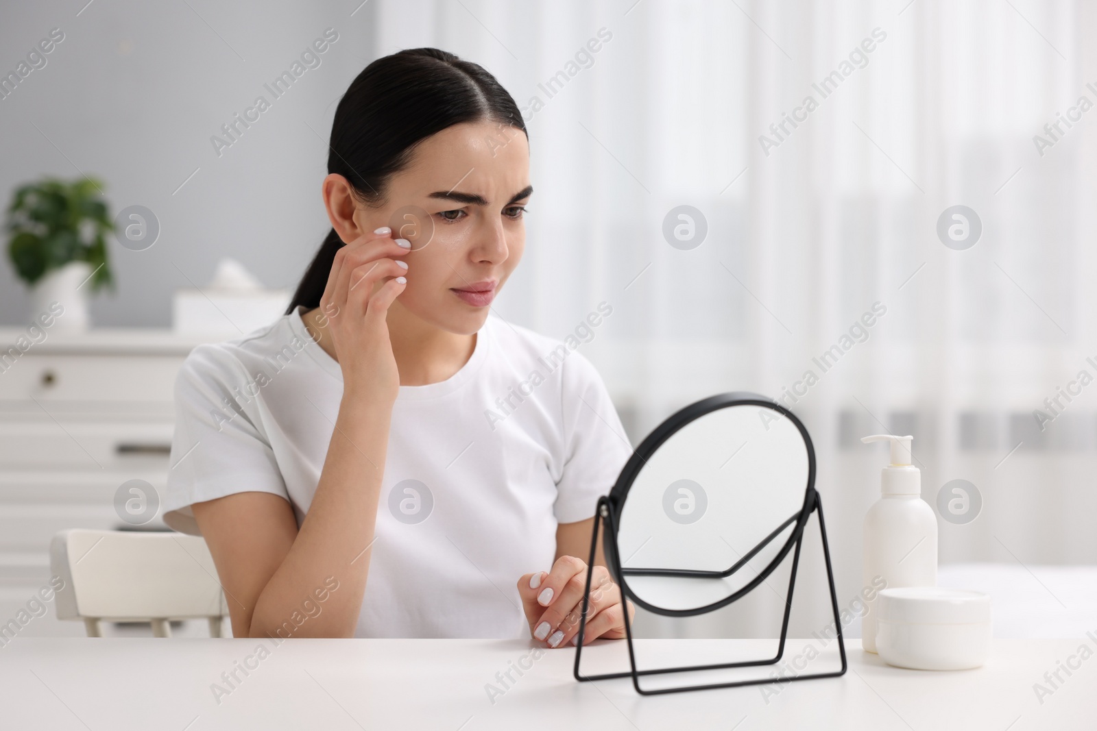 Photo of Woman with dry skin looking at mirror indoors