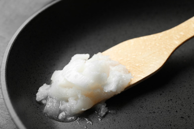 Frying pan with coconut oil and wooden spatula, closeup. Healthy cooking