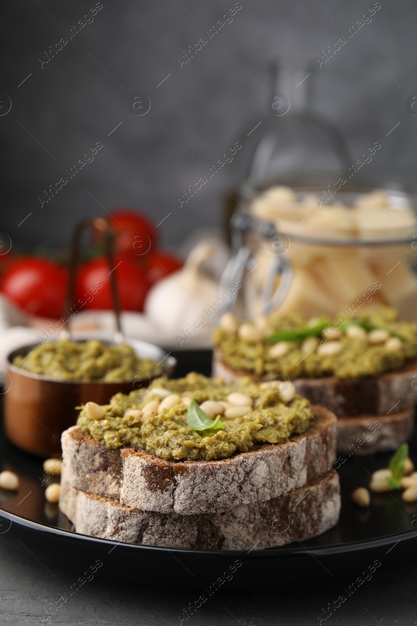 Photo of Tasty bruschettas with pesto sauce and nuts on plate, closeup