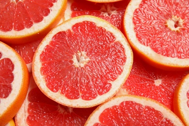 Photo of Many sliced fresh ripe grapefruits as background, closeup