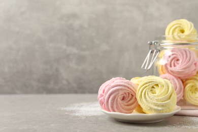 Photo of Delicious pink and yellow marshmallows on grey table. Space for text