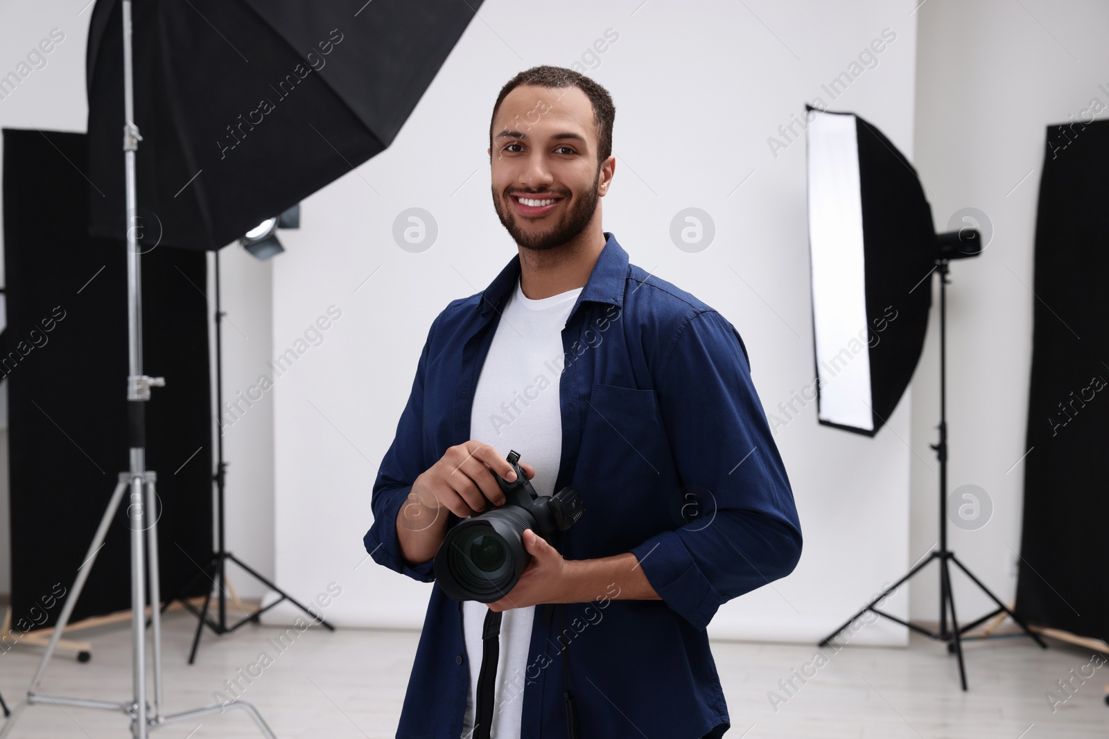 Photo of Young professional photographer with camera in modern photo studio