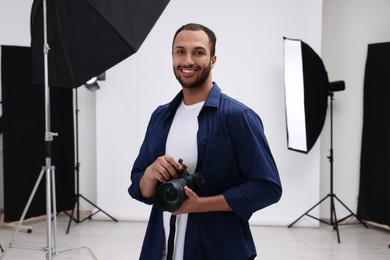 Young professional photographer with camera in modern photo studio