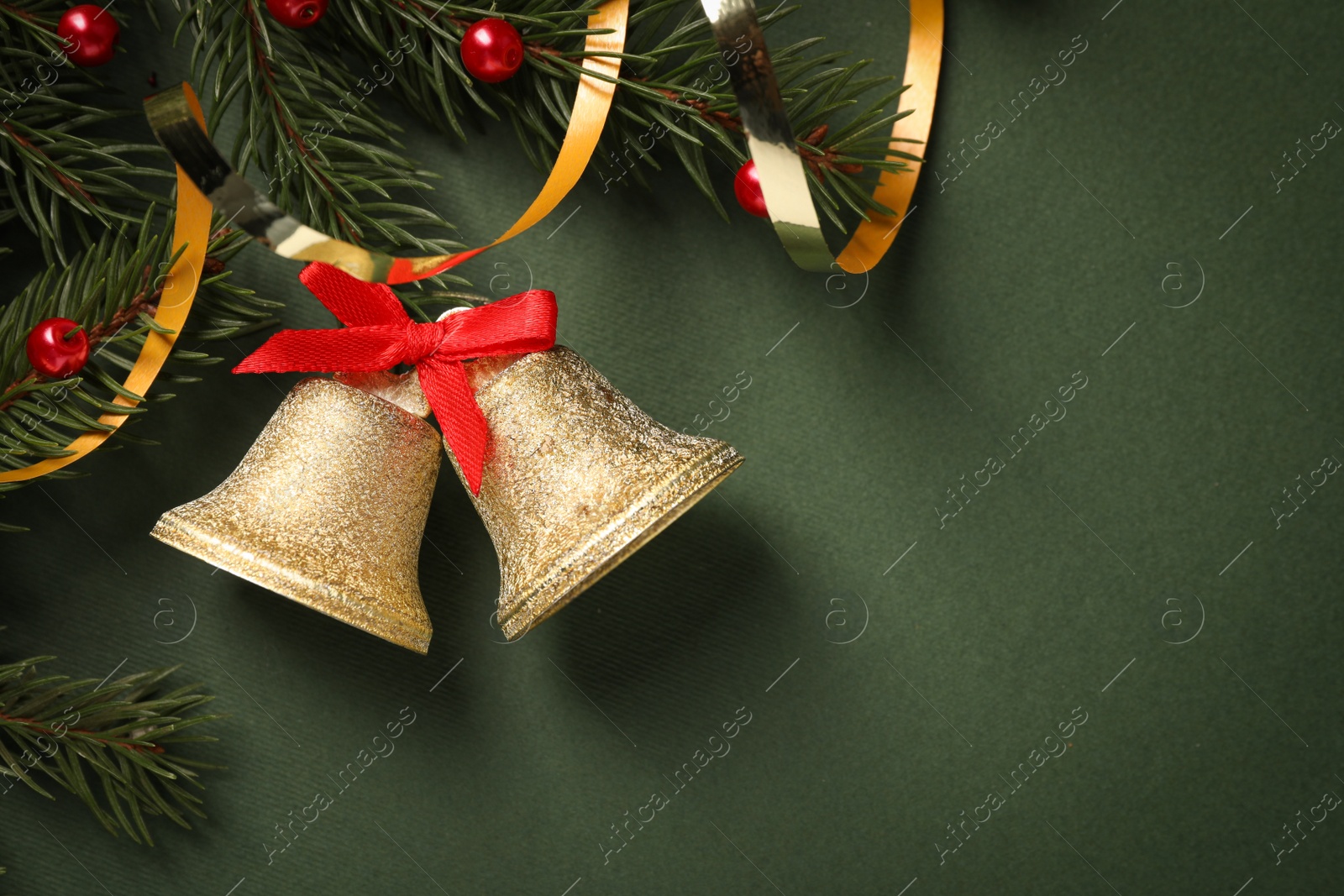 Photo of Bells and fir branches with Christmas decor on dark green background, flat lay. Space for text