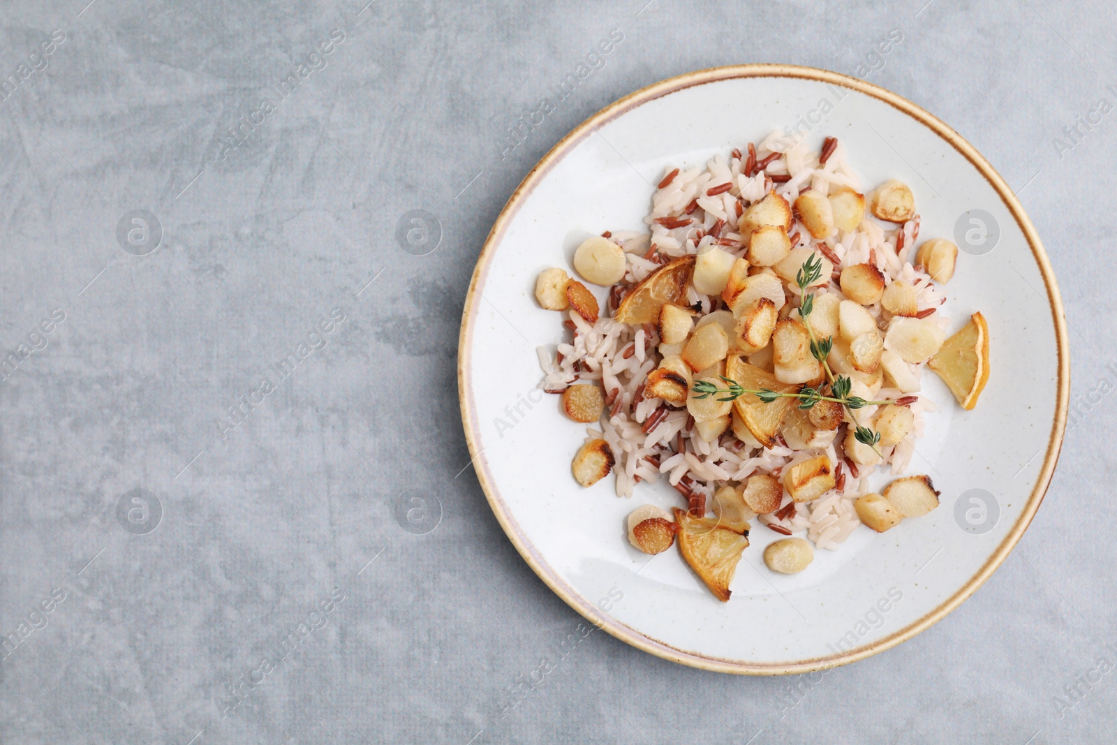 Photo of Plate with baked salsify roots, lemon and rice on light grey table, top view. Space for text