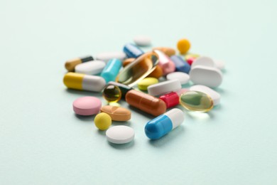 Photo of Pile of different pills on mint background, selective focus