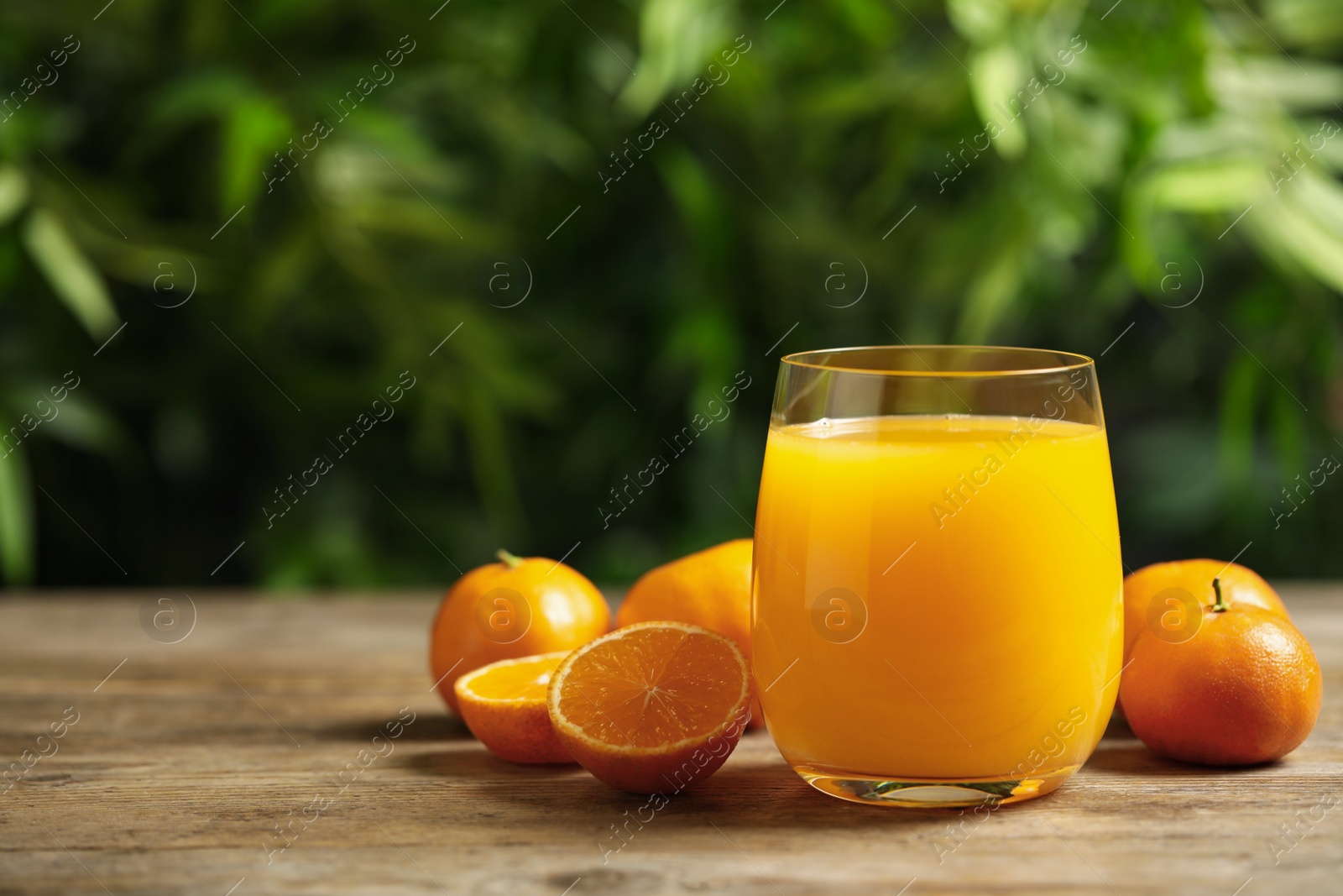 Photo of Glass of fresh tangerine juice and fruits on wooden table. Space for text