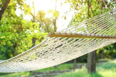 Photo of Comfortable net hammock hanging in green garden, closeup