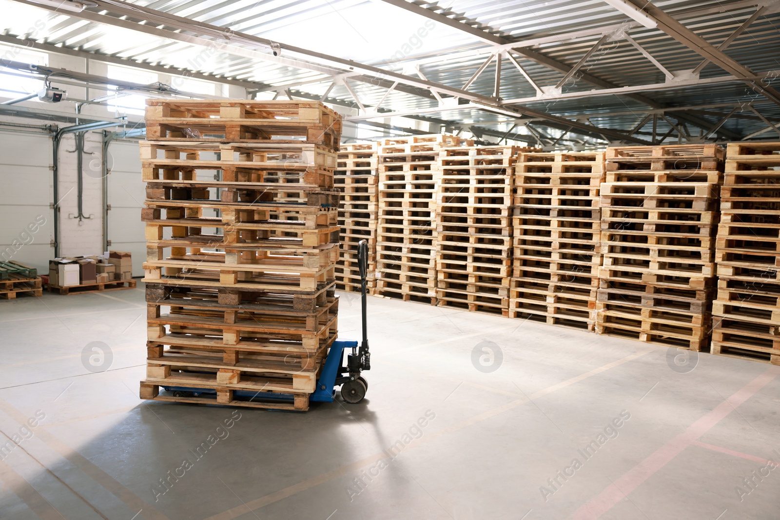 Image of Modern manual forklift with wooden pallets in warehouse, space for text