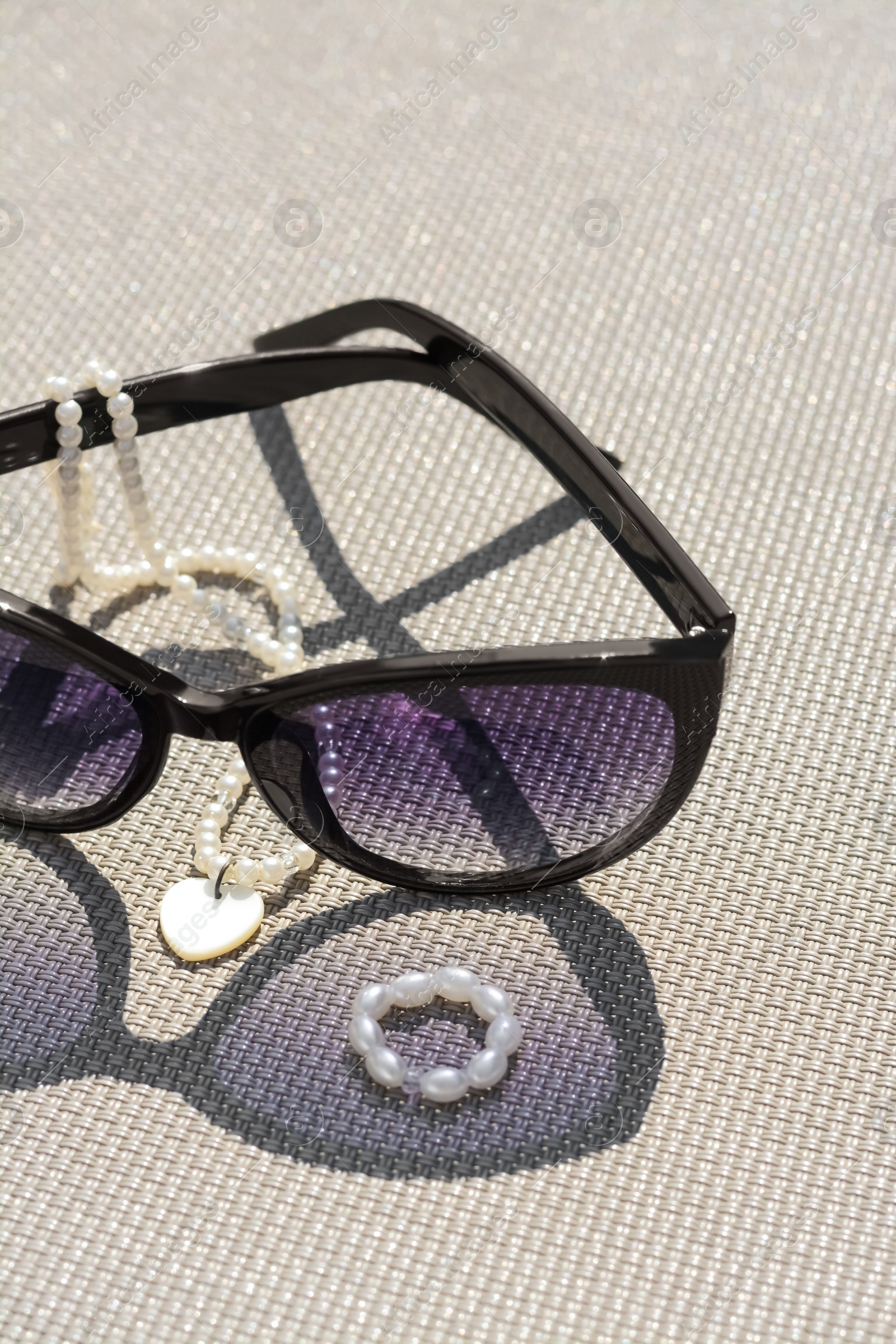 Photo of Stylish sunglasses and jewelry on grey surface, closeup