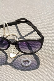 Stylish sunglasses and jewelry on grey surface, closeup