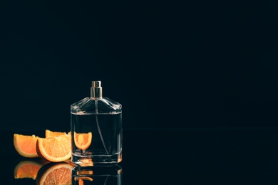 Perfume bottle and slices of citrus fruit on black background