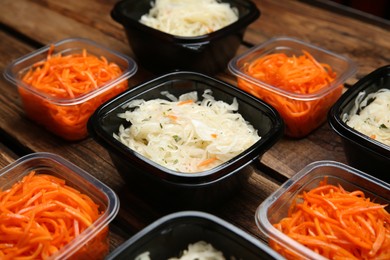 Photo of Plastic containers with tasty vegetable salads on wooden table, closeup. Food delivery service