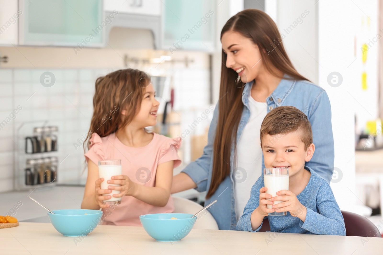 Photo of Happy family having breakfast with milk in kitchen