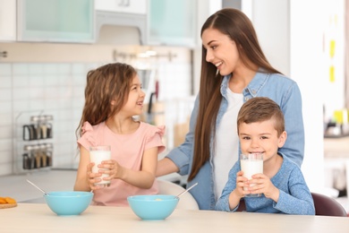 Photo of Happy family having breakfast with milk in kitchen