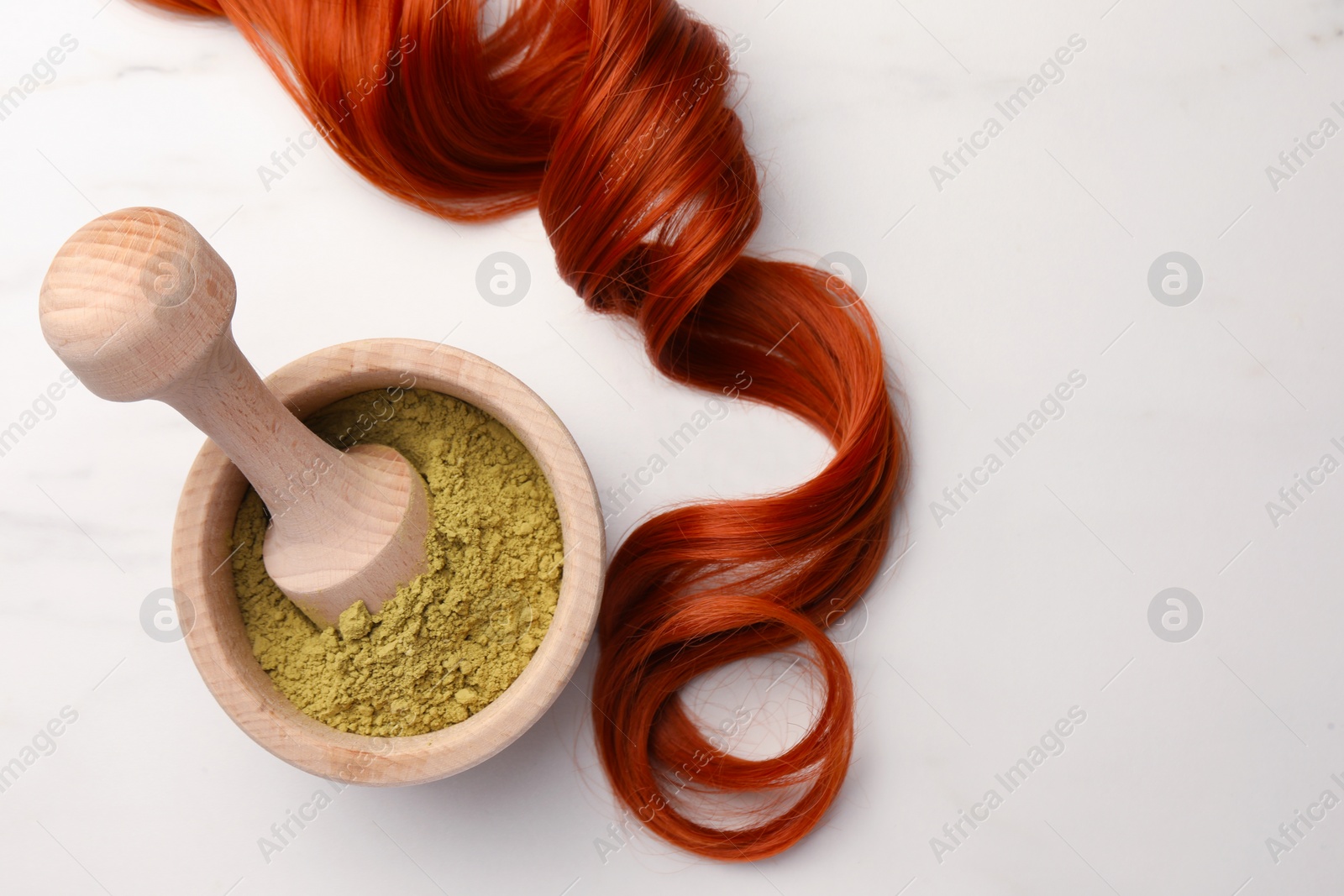 Photo of Mortar of henna powder and red strand on white marble table, flat lay with space for text. Natural hair coloring