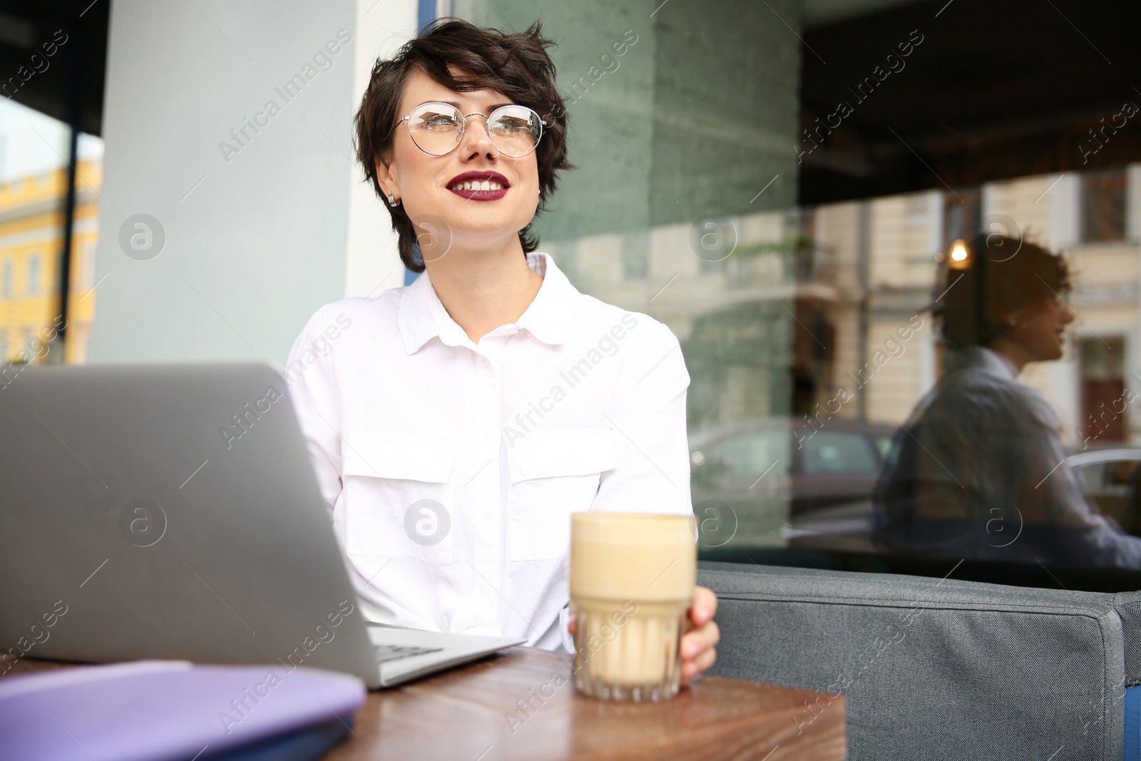 Photo of Young woman working with laptop at desk in cafe