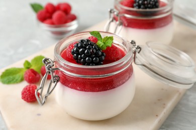 Photo of Delicious panna cotta with fruit coulis and fresh berries on light table